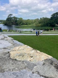 a rocky terrain, below is well maintained grass before overlooking the lake