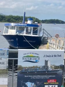the lily of killarney watercoach. behind the sign is the waterbus docked on the pier