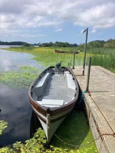 a single boat docked onto a pier floating in shallow water.
