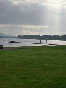 green grass with a lake in the distance, rays of sunshine being shined onto the lake